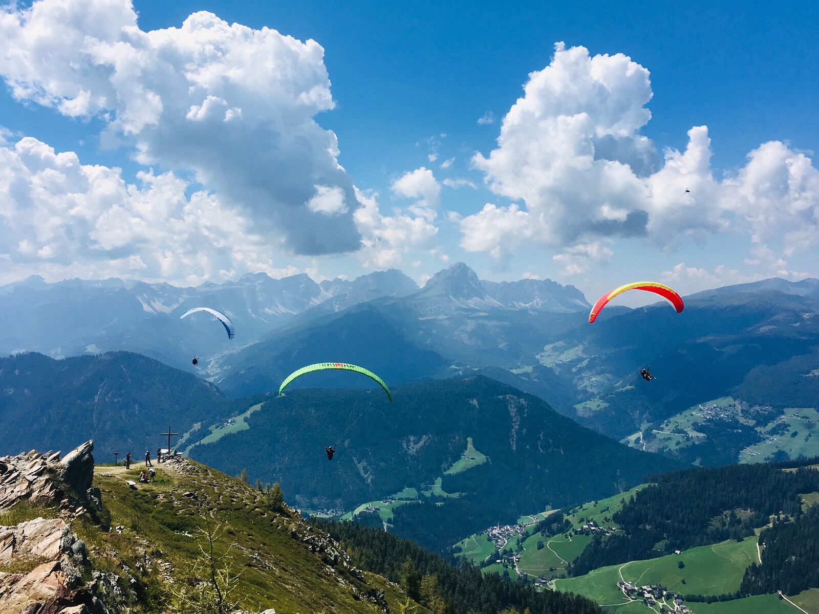 Mehrere Gleitschirme über dem grünen Tal