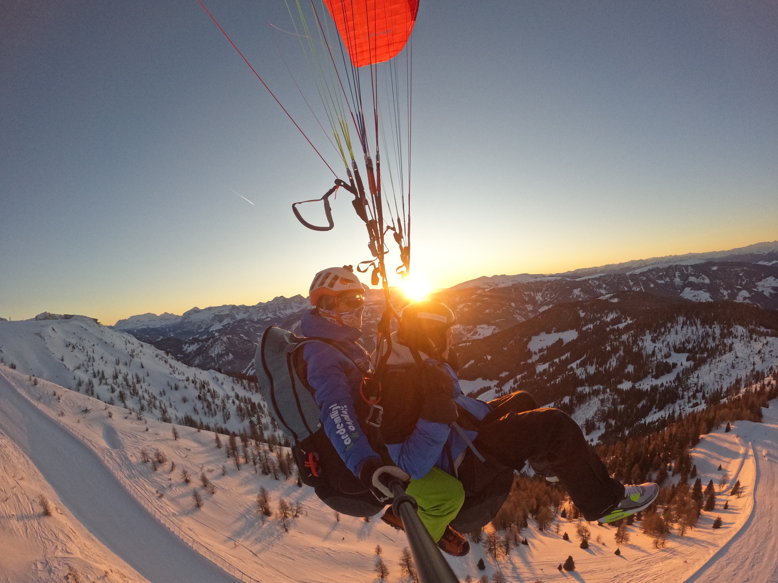 Tandemflug über verschneiten Bergen im Abendlicht